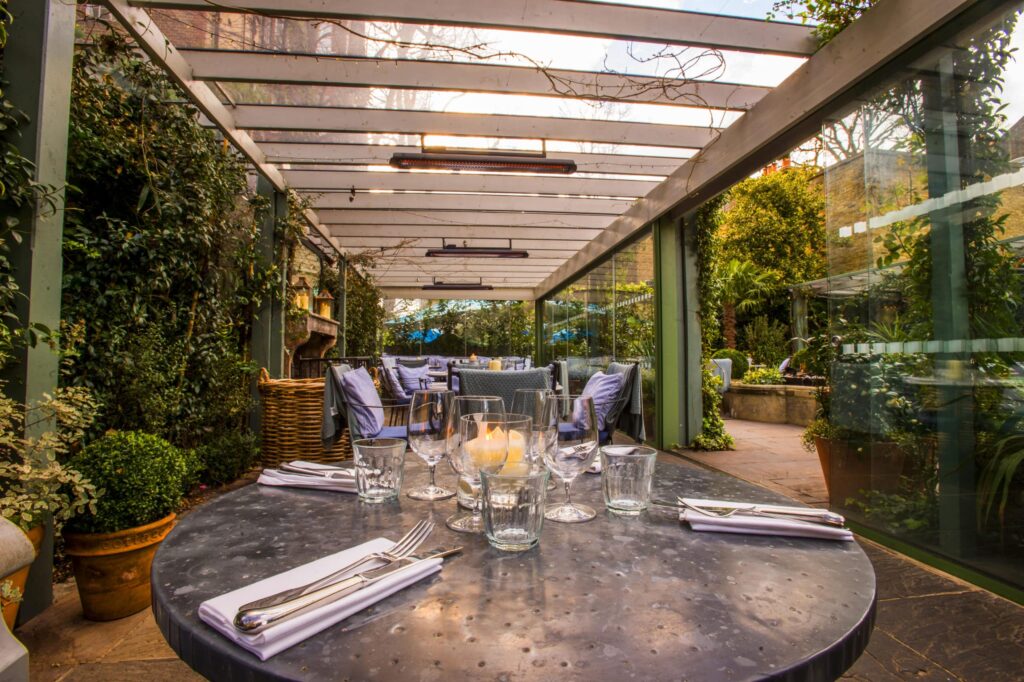 Close up of pre set restaurant table in beautiful covered garden restaurant and electric heaters